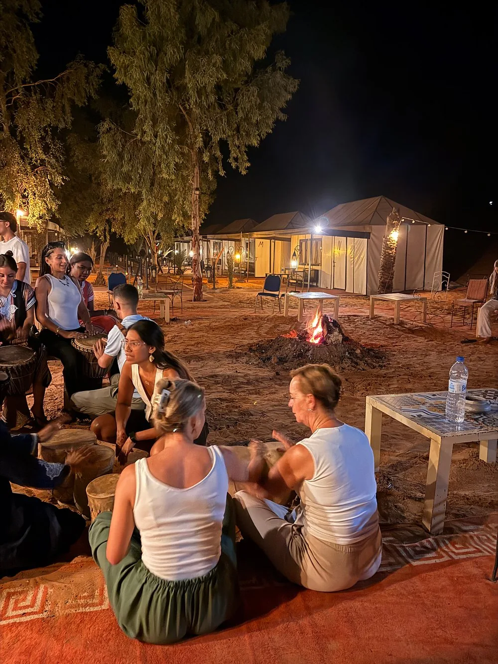 Evening around the fire at a Merzouga desert camp Travellers sitting around a fire playing drums at a desert camp near Merzouga at night